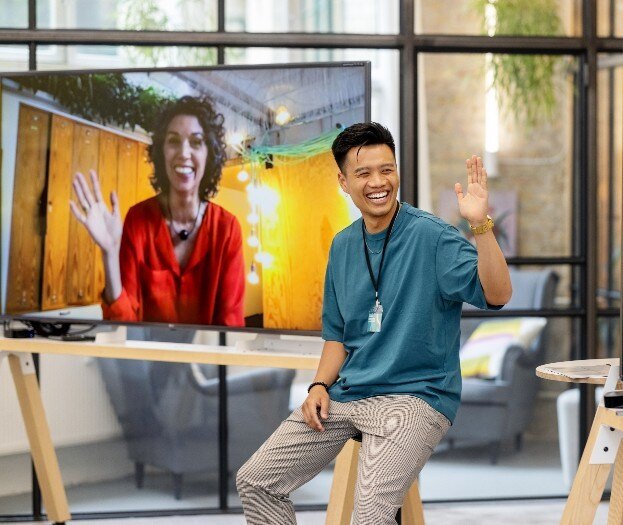 8587-SG-Young businessman waving to colleagues on screen